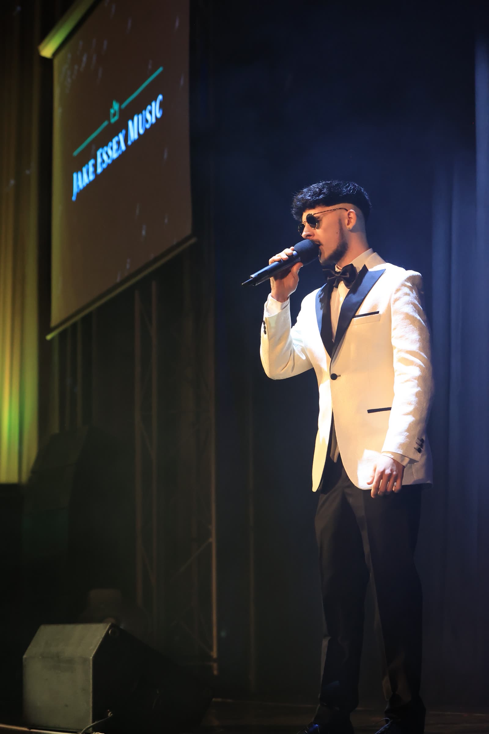 Jake Essex on stage with the Jake Essex Music screen